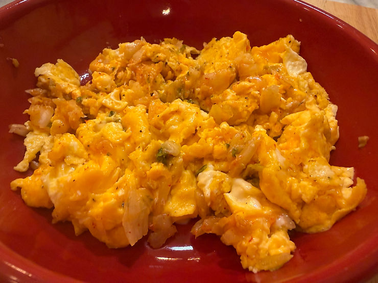 Close-up view of scrambled eggs folded with finely chopped kimchee on a white plate